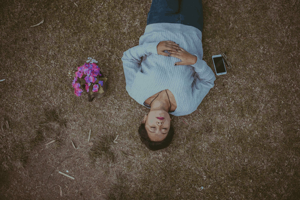 woman lying on ground with cell phone by Cristian Newman